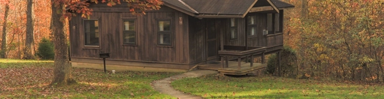 Cabin nestled among colorful autumn trees with a walking path leading to the front entrance.